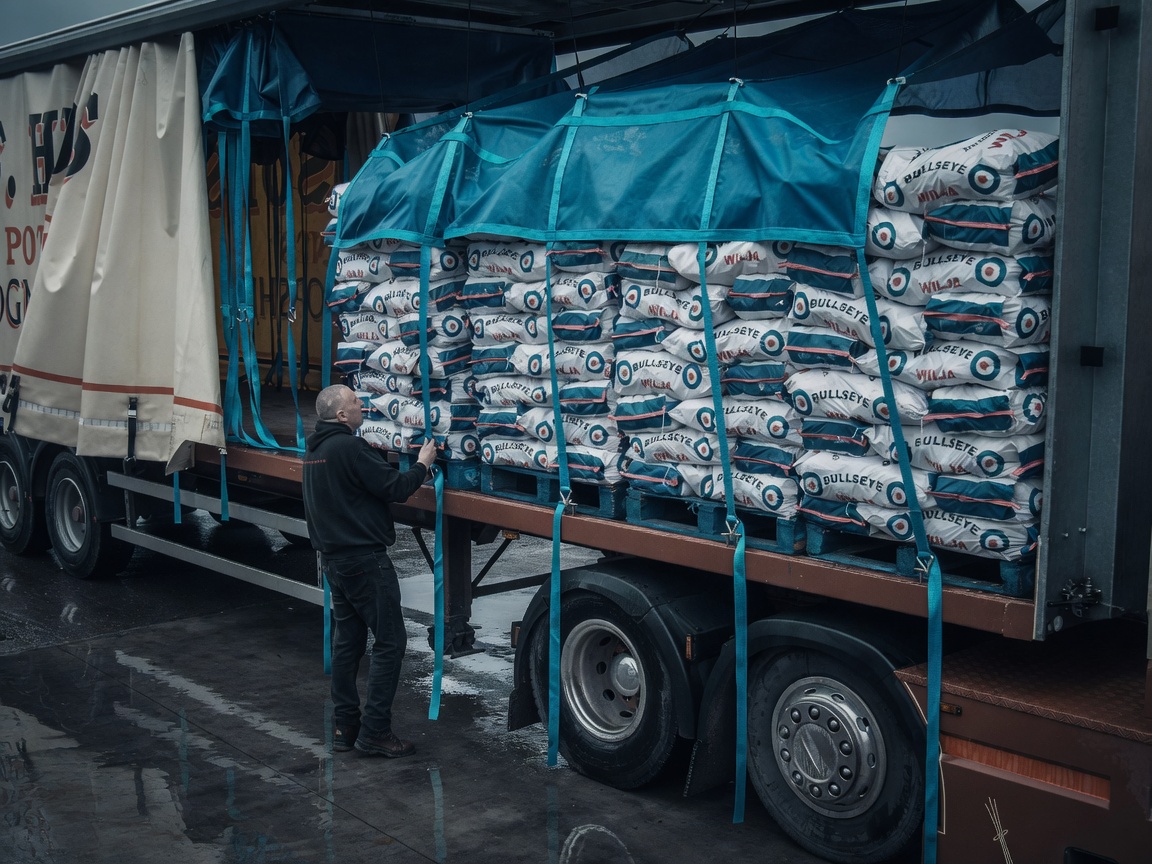 Net assembly over bagged cargo being tensioned at the trailer side